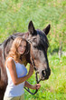 Young girl walking with a horse in the garden.