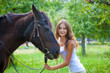 Young girl walking with a horse in the garden.