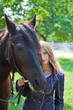 Young girl walking with a horse in the garden.