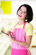 Young woman in apron using tablet computer