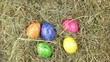 A hand cvollects a few estaer eggs from a pile of straw.