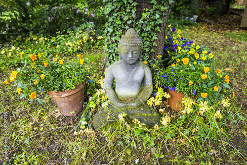 Photo: buddha statue in sitting position under a cherry tree buddha statue in sitting position under a cherry tree