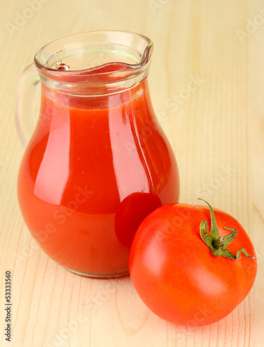 Photo: Full jug of tomato juice, on wooden background Full jug of tomato juice, on wooden background