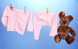Baby clothes hanging on clothesline, on color background