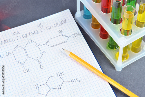 Photo: Test tubes with colorful liquids and formulas on grey Test tubes with colorful liquids and formulas on grey