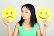 Young woman holding paper with sad and happy smiley