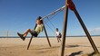 Happy boys swinging with the beach on background