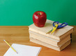 Red apple and scissors on pile of books