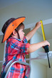Cute little boy measuring a part of cupboard