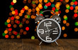Bokeh spots of lights with alarm clock on wood