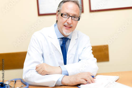 Photo: Mature doctor at his desk in his studio Mature doctor at his desk in his studio