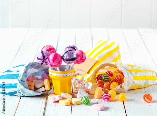 Photo: Assortment of candies in bags and cup over a table Assortment of candies in bags and cup over a table