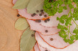 Sliced of ham and herbs with spiceson wooden background