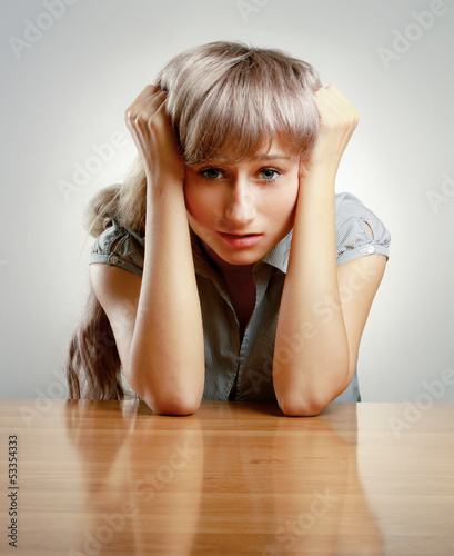 Photo: A young tired woman sitting at the desk A young tired woman sitting at the desk