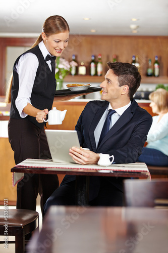 Photo: Kellnerin bedient Geschäftsmann im Café Kellnerin bedient Geschäftsmann im Café