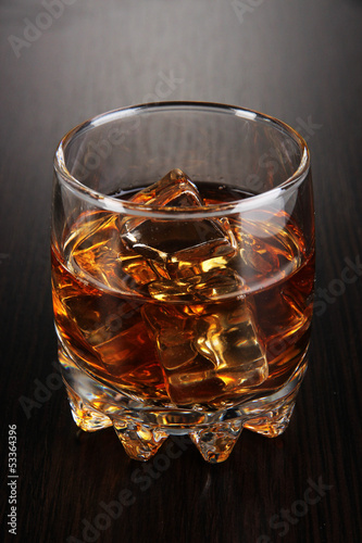 Photo: Brandy glass with ice on wooden background Brandy glass with ice on wooden background