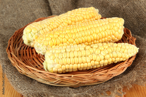 Photo: Fresh corn on wicker mat, on sackcloth background Fresh corn on wicker mat, on sackcloth background