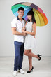 Beautiful loving couple with umbrella on grey background