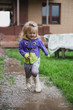 Funny 2 years old baby girl playing in puddle.