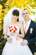 bride and groom outside against yellow leaves background