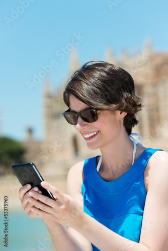 Photo: lächelnde touristin schaut auf ihr handy lächelnde touristin schaut auf ihr handy