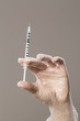 closeup of womans hand wearing latex gloves holding syringe