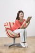 Foto: Happy Chinese woman sitting on a chair using Digital Tablet Happy Chinese woman sitting on a chair using Digital Tablet