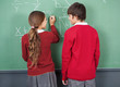Foto: Students Looking At Each Other While Writing On Board Students Looking At Each Other While Writing On Board