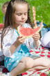 Pretty little girl eating watermelon in the park