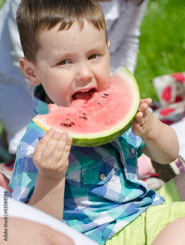 Photo: Portrait of a boy eating watermelon in the park Portrait of a boy eating watermelon in the park