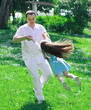 Father and daughter spinning in summer park