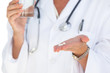 Foto: Doctor holding out tablets and water glass Doctor holding out tablets and water glass