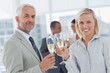 Business team celebrating with champagne and looking at camera