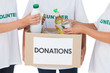 Group of volunteers putting food in donation box