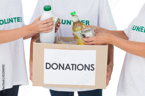 Photo: Group of volunteers putting food in donation box Group of volunteers putting food in donation box