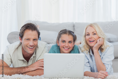 Photo: Cheerful parents and daughter using a laptop Cheerful parents and daughter using a laptop