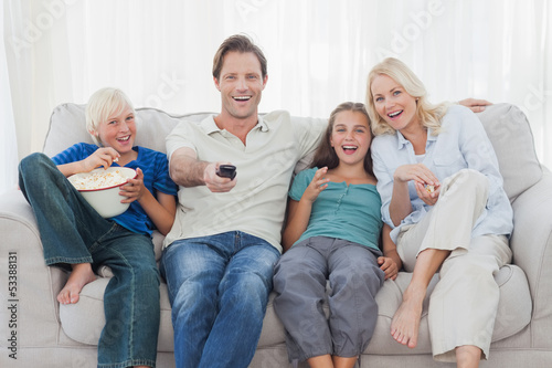Photo: Family watching television sitting on sofa Family watching television sitting on sofa