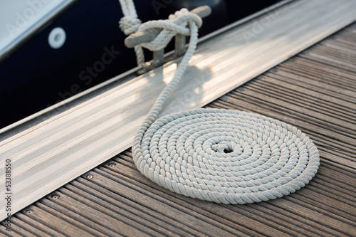 Photo: White rope coiled on a wooden dock White rope coiled on a wooden dock