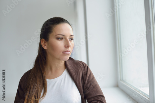 Photo: pensive woman near the window pensive woman near the window