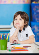Foto: Boy Sitting With Hand On Chin In Drawing Class Boy Sitting With Hand On Chin In Drawing Class