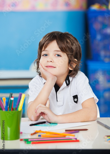 Photo: Boy Sitting With Hand On Chin In Drawing Class Boy Sitting With Hand On Chin In Drawing Class
