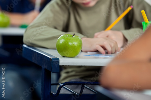 Photo: Schoolboy Writing In Book With Apple At Desk Schoolboy Writing In Book With Apple At Desk