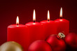 Vier rote Kerzen und Weihnachtsbaumkugeln