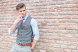 casual man smoking by brick wall