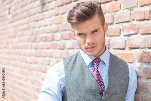 Photo: casual man next to a brick wall casual man next to a brick wall