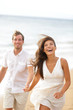 Beach fun - couple laughing and running together