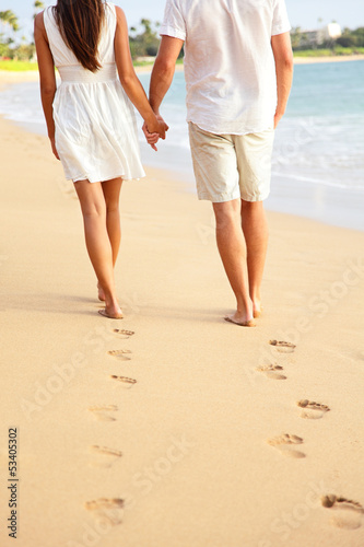 Photo: Couple holding hands walking on beach on vacation Couple holding hands walking on beach on vacation