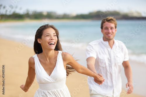 Photo: Beach couple running having fun laughing together Beach couple running having fun laughing together