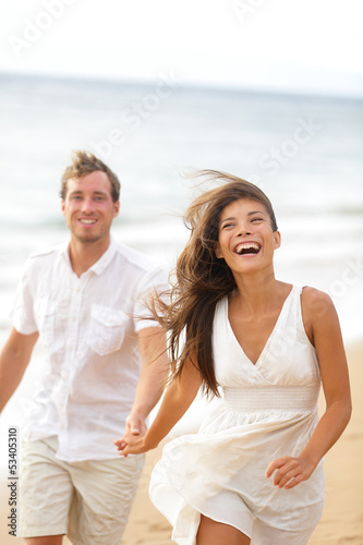 Photo: Beach fun - couple laughing and running together Beach fun - couple laughing and running together