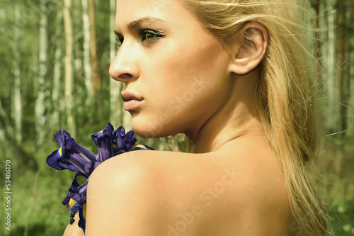 Photo: Beautiful blond woman with blue flowers in a forest Beautiful blond woman with blue flowers in a forest